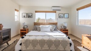 Een slaapkamer met een groot bed, twee nachtkastjes, een houten hoofdbord en ingelijste foto's aan de muur.