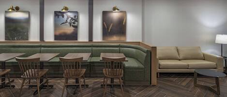A modern restaurant with a green cushioned bench, wooden tables, and chairs.
