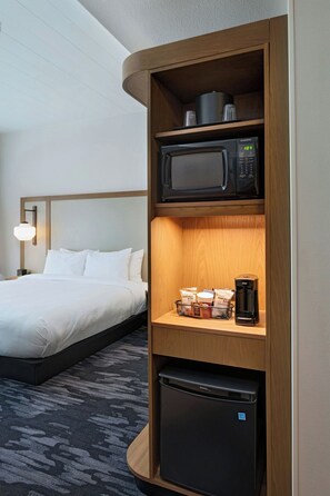 Ein Hotelzimmer mit einem Bett, einer Mikrowelle, einer Kaffeemaschine und einem kleinen Kühlschrank.