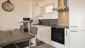 A modern kitchen with white cabinets, a stainless steel range hood, a Bosch oven, and a microwave. - 1 bedroom gorgeous apartment in Ajaccio (Ajaccio)