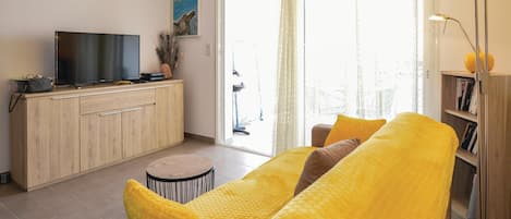 A modern living room with a sofa, a television, a small round table, and a bookshelf.