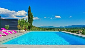 A swimming pool with pink lounge chairs and a view of a mountainous landscape. - Luxurious home in Glavina Donja (Glavina Donja)