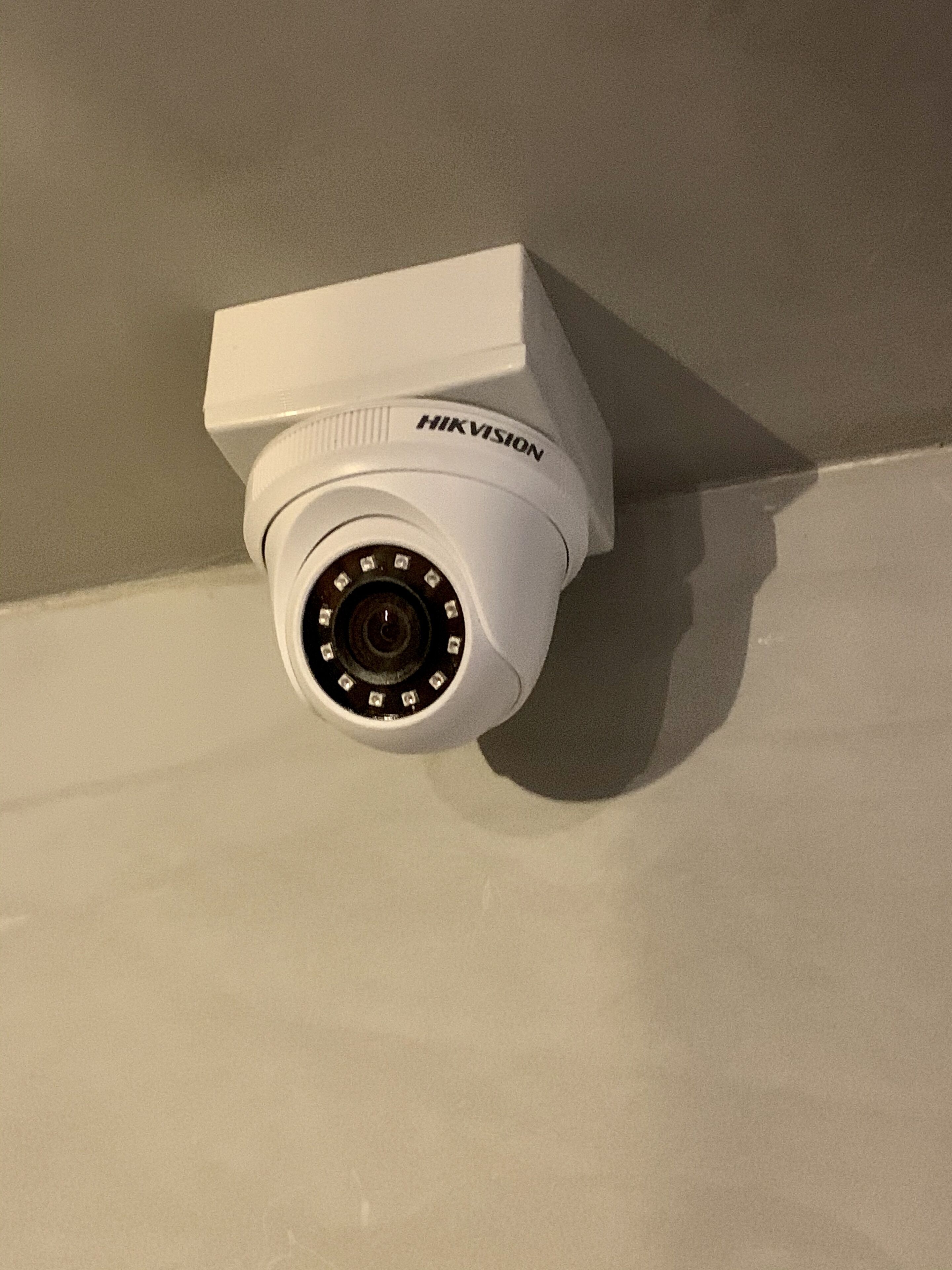 A white Hikvision security camera mounted on a wall.