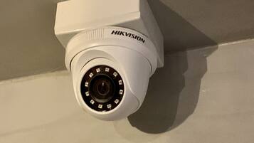 A white Hikvision security camera mounted on a wall.