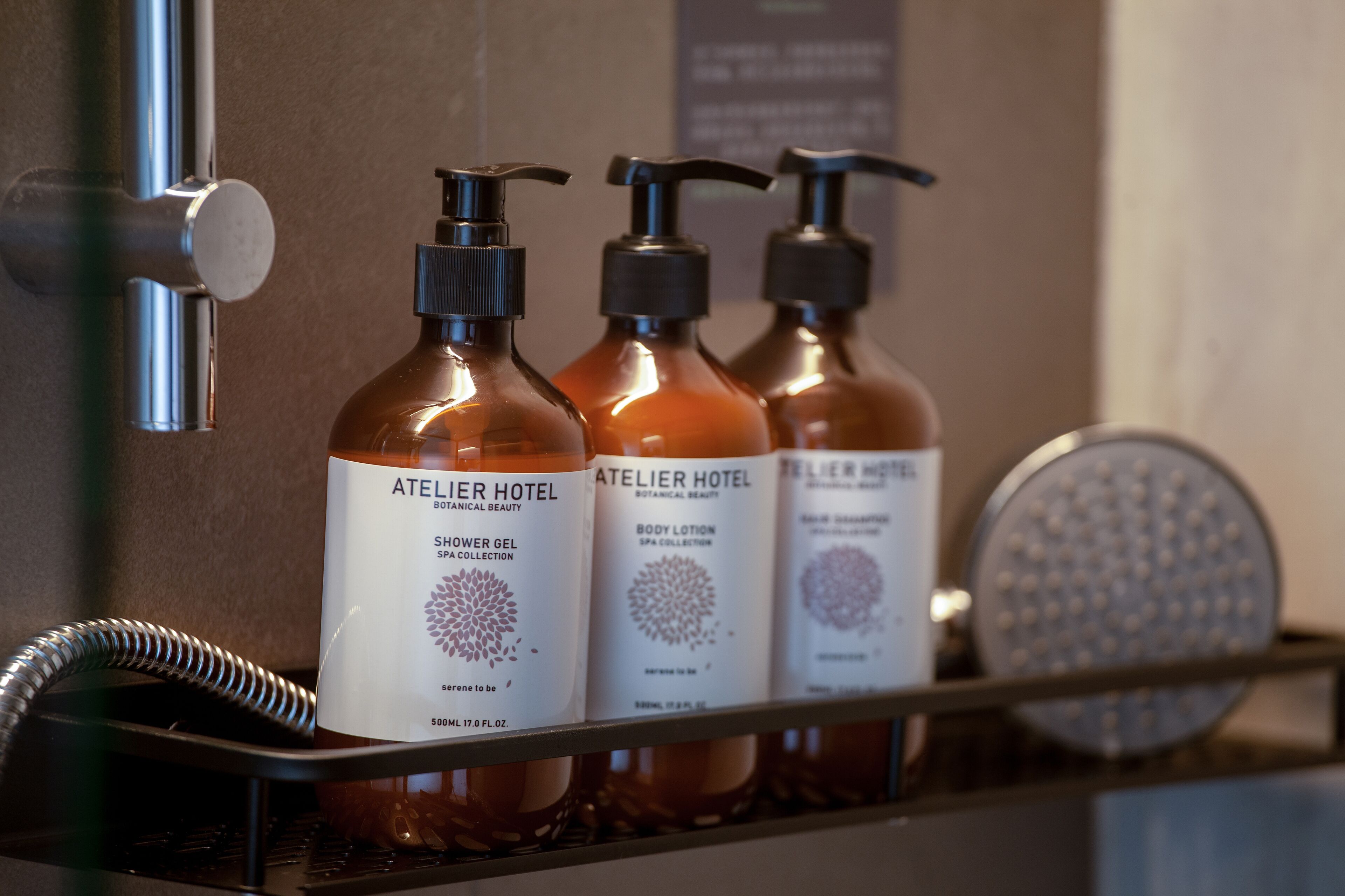 A bathroom with three bottles of shower gel, a body lotion, and a handheld showerhead.