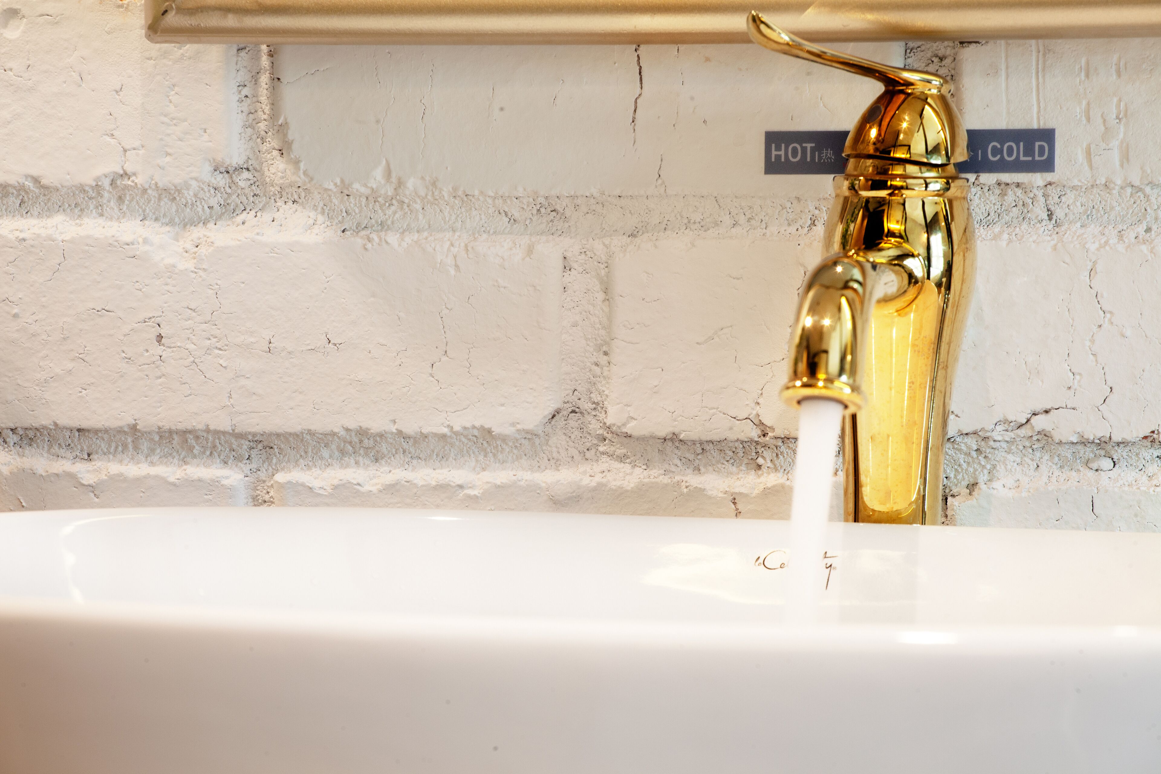 A gold faucet with a hot and cold water control.