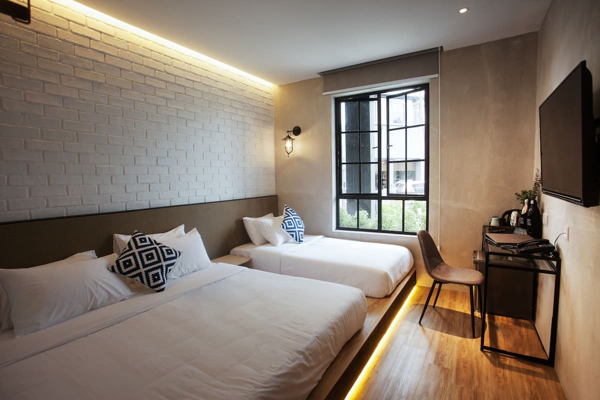 A hotel room with two beds, a desk, and a chair.