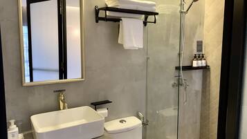A modern bathroom with a glass-enclosed shower, a white sink, and a toilet.