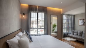 Et moderne hotelværelse med en stor seng, en sofa, et lille bord og et spejl.