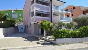 A multi-story residential building with balconies, a paved entrance, and surrounding greenery. - Apartment Marjolovic 1 (Njivice)