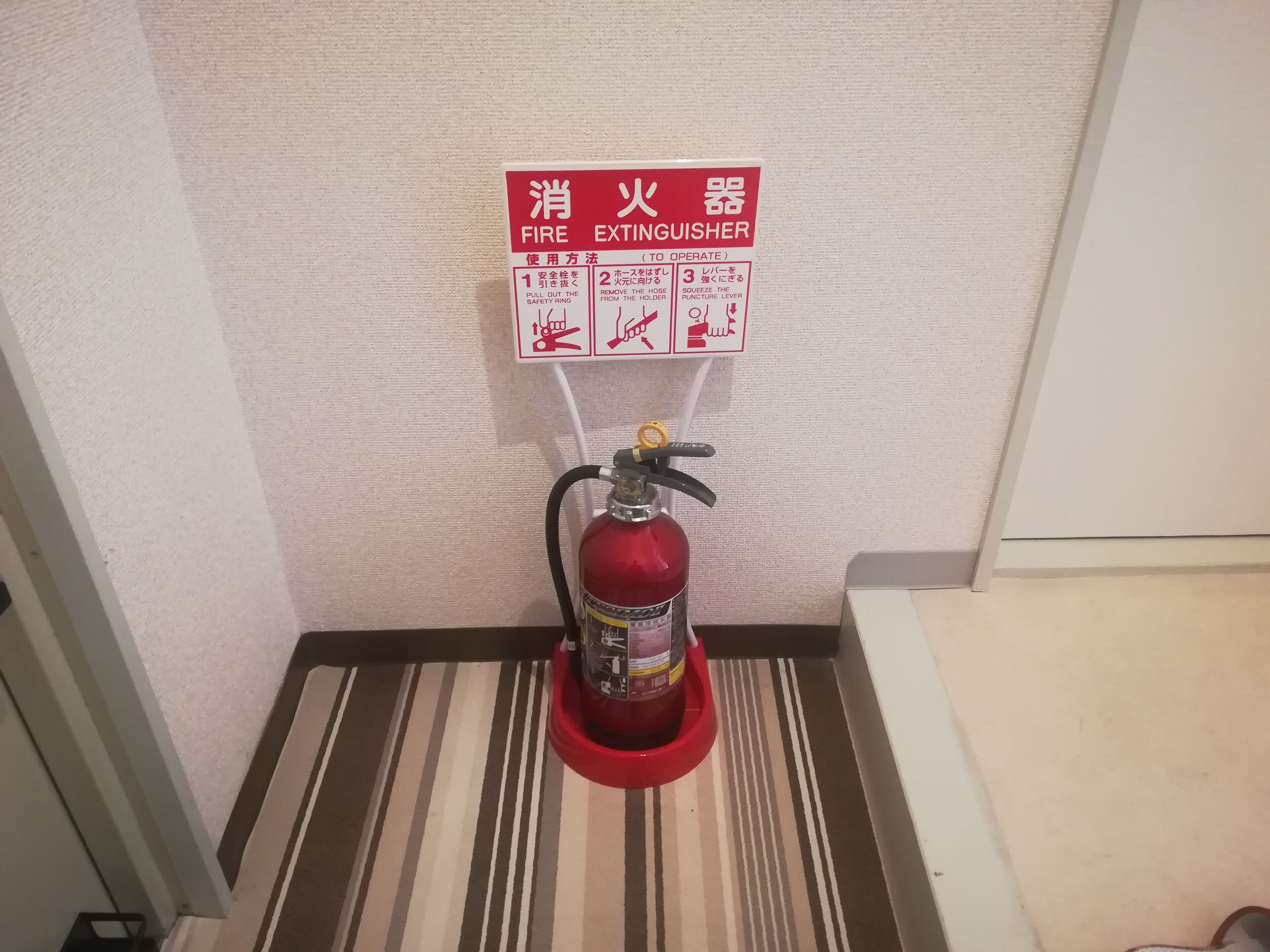 A fire extinguisher mounted on a wall with a safety instruction sign above it.