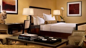 A hotel room with a bed, two bedside tables with lamps, a desk with a chair, a coffee table with books, and a decorative plant. - 2. 2 miles to convention center (Las Vegas)
