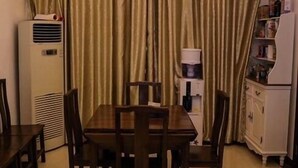 A dining area with a table and chairs, a chandelier, curtains, and a refrigerator. - Tea farmer Inn in West Lake Hangzhou (Hangzhou)
