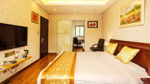 A hotel room with a large bed, a television, a desk with a chair, and a bathroom visible through a glass door. - Tea farmer Inn in West Lake Hangzhou (Hangzhou)