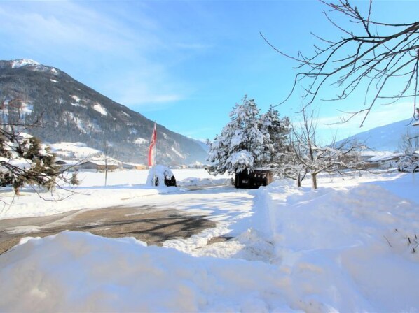 A snowy landscape with a mountain in the background, a road, and a small building with a flag.