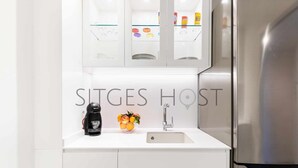 A modern kitchen with a stainless steel refrigerator, a coffee maker, and a sink with a glass bowl of fruit. - Beautiful Seafront Views (Sitges)