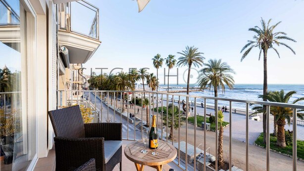 A balcony with wicker furniture, a bottle of champagne, and a view of the beach and ocean. - Beautiful Seafront Views (Sitges)