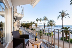 A balcony with wicker furniture, a bottle of champagne, and a view of the beach and ocean. - Beautiful Seafront Views (Sitges)