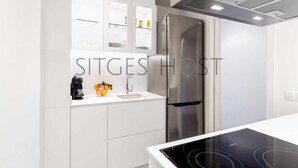 A modern kitchen with a stainless steel refrigerator, a built-in oven, and a white countertop. - Beautiful Seafront Views (Sitges)