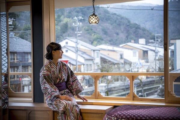 A person sitting by a window with a view of a residential area. - Sumihei Bettei Tokitotoki (Toyooka)