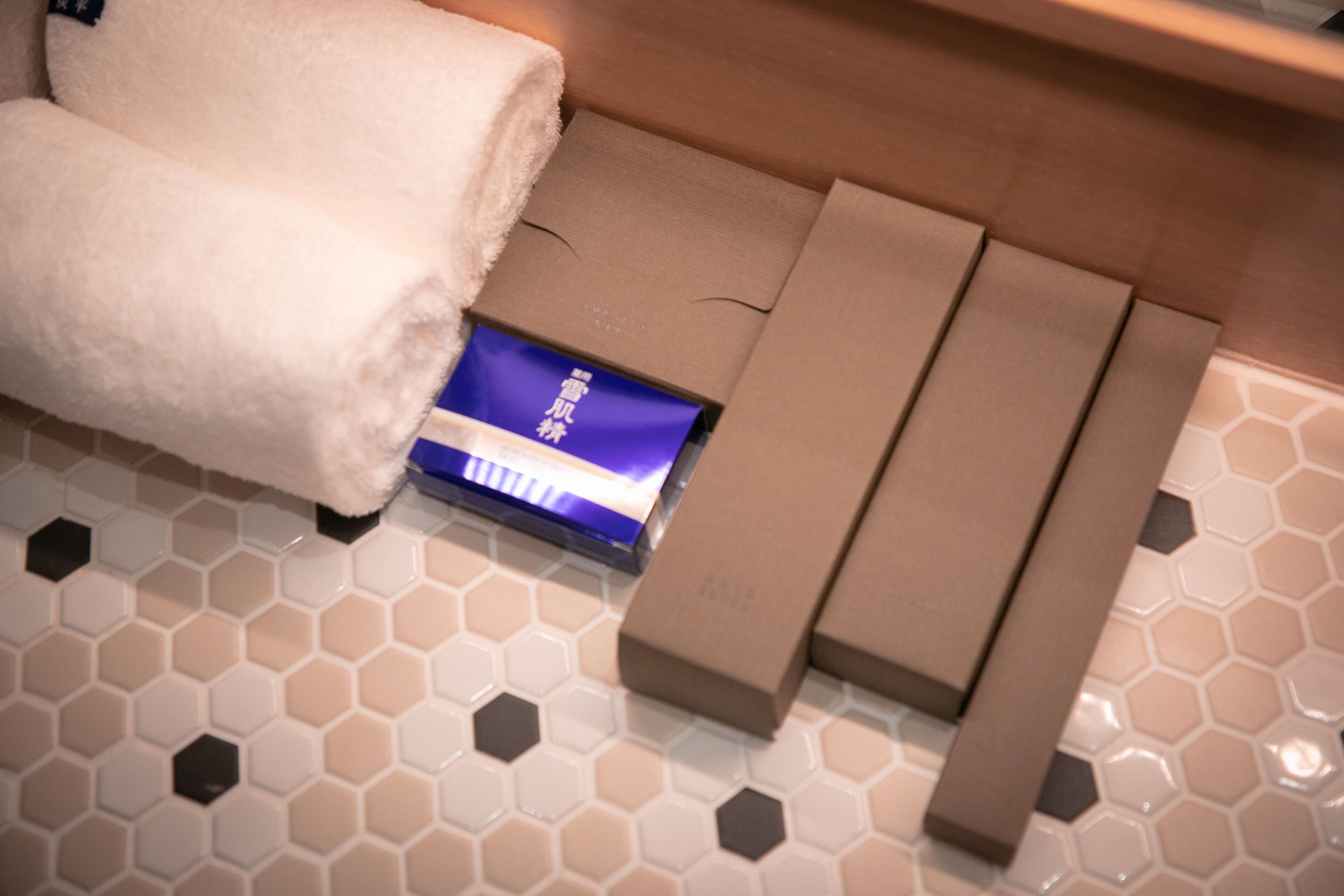 A bathroom with a towel, a blue card, and a brown bench.