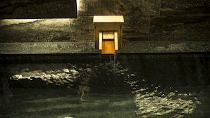 A wooden water feature with a wooden box structure, set against a stone wall. - Sumihei Bettei Tokitotoki (Toyooka)