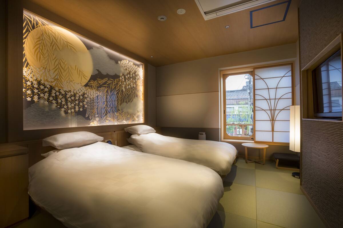 A traditional Japanese-style room with tatami flooring, a large wall mural, and a sliding door leading to a balcony.