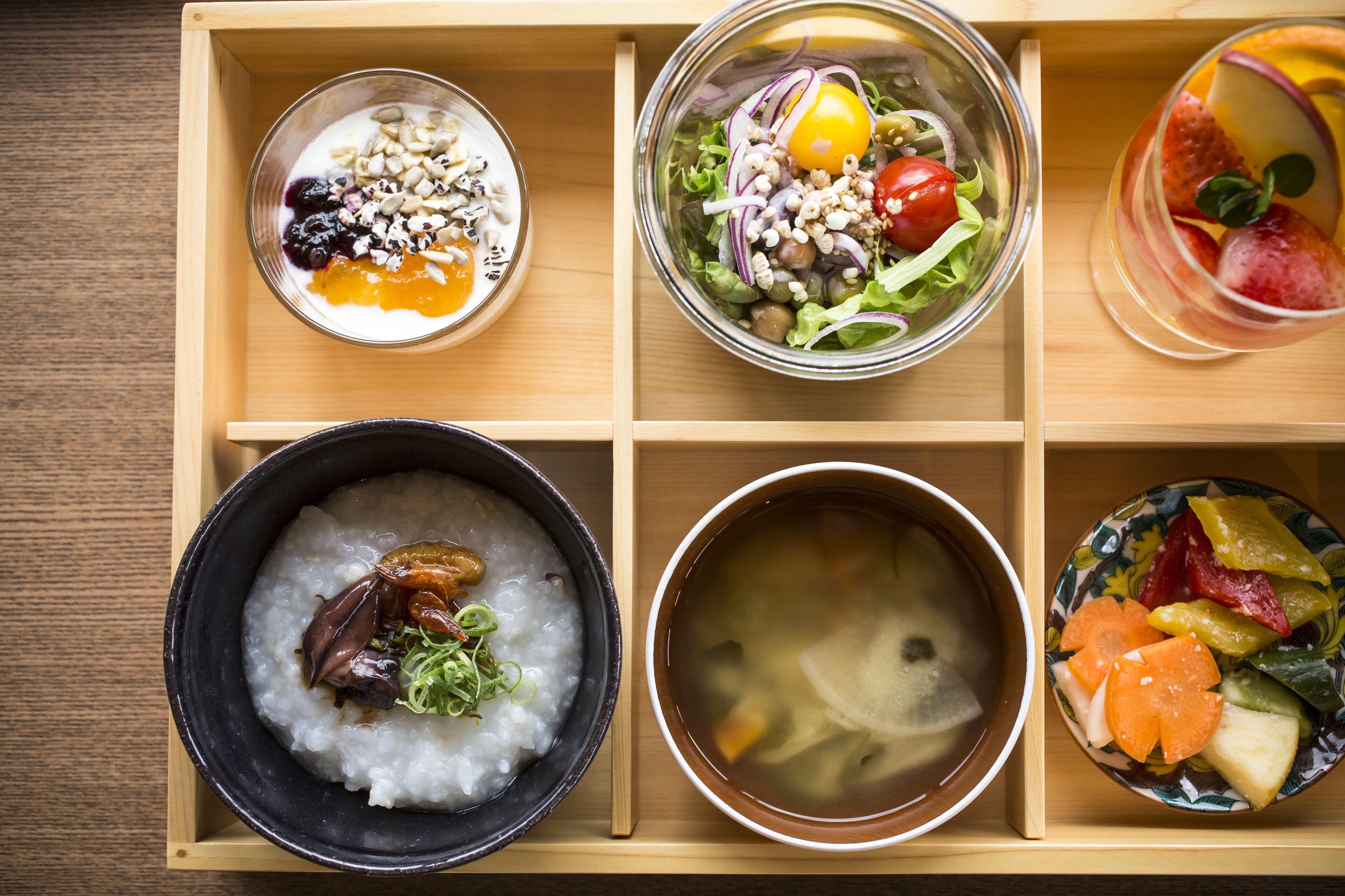 A wooden tray with six compartments containing various dishes.