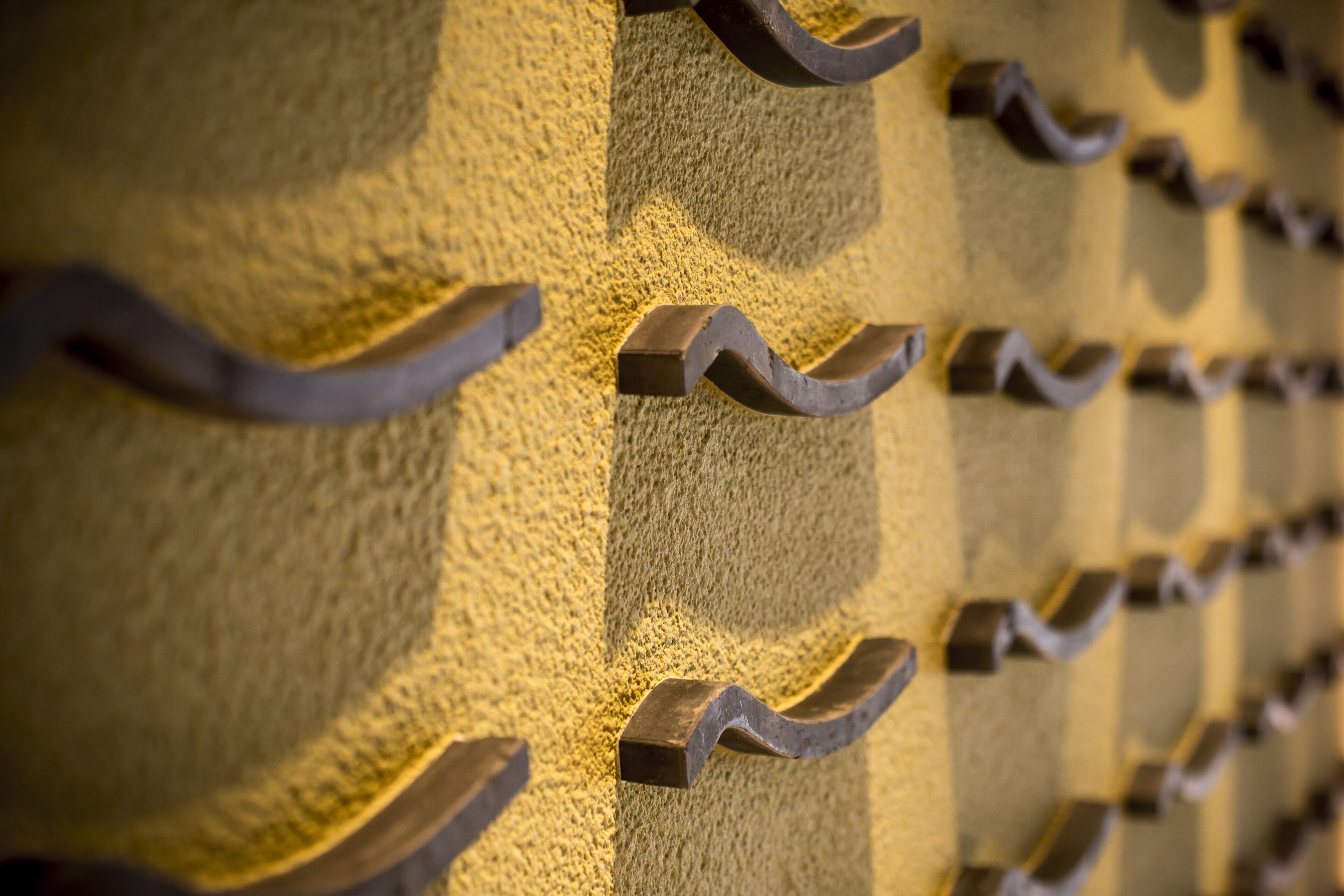 A close-up of a textured wall with a series of metal hooks.