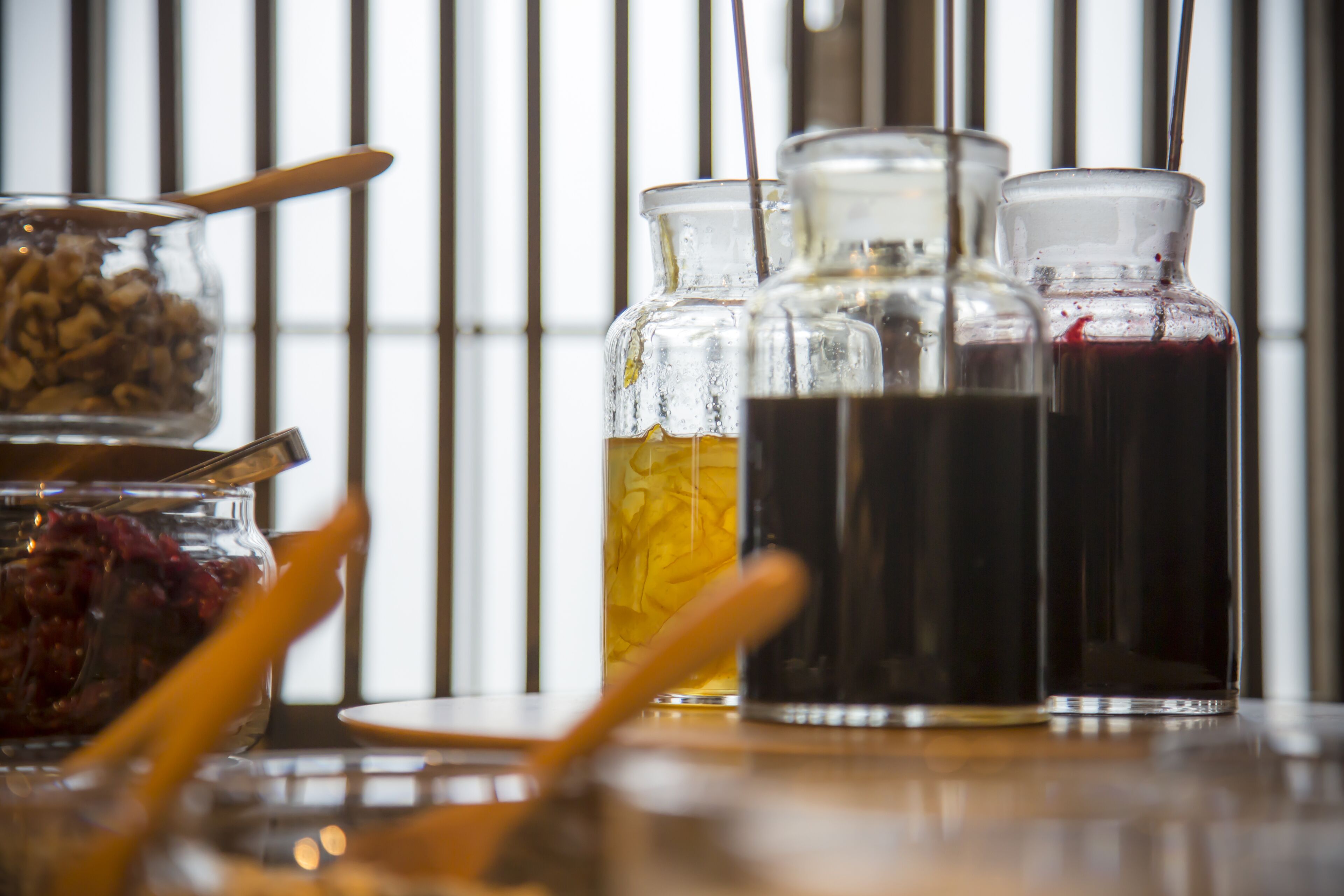 A table with glass containers holding various liquids and a bowl of cereal.