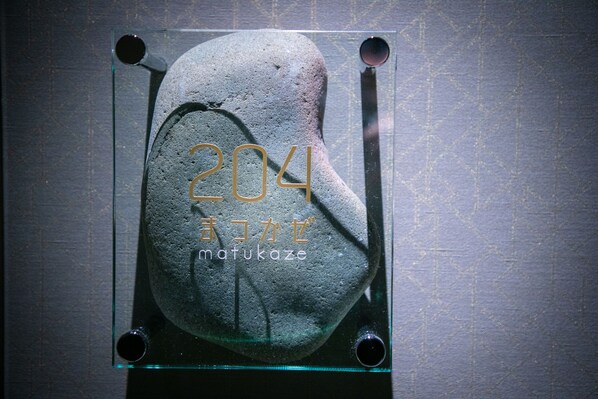 Una piedra con el número 204 y caracteres japoneses grabados, exhibida en una vitrina.