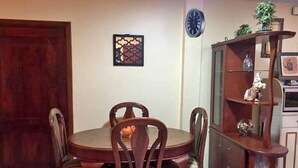 A dining area with a round table and four chairs, a wooden cabinet with glass doors, and a clock on the wall. - Alquilo Apartamento Centro Guayaquil (Guayaquil)