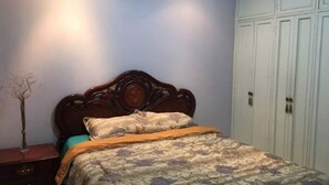 A bedroom with a wooden bed, a nightstand, and a wardrobe. - Alquilo Apartamento Centro Guayaquil (Guayaquil)