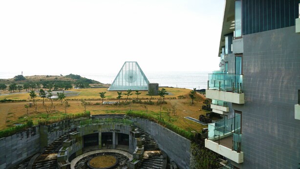 Un hôtel moderne doté d’une structure unique en forme de pyramide de verre, d’une cour intérieure circulaire et offrant une vue sur la plage.