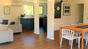 A modern living space with a dining area, kitchen, and a large window providing natural light.
