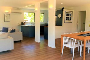 A modern living space with a dining area, kitchen, and a large window providing natural light.