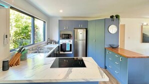 A modern kitchen with a central island, built-in appliances, and a large window providing natural light.