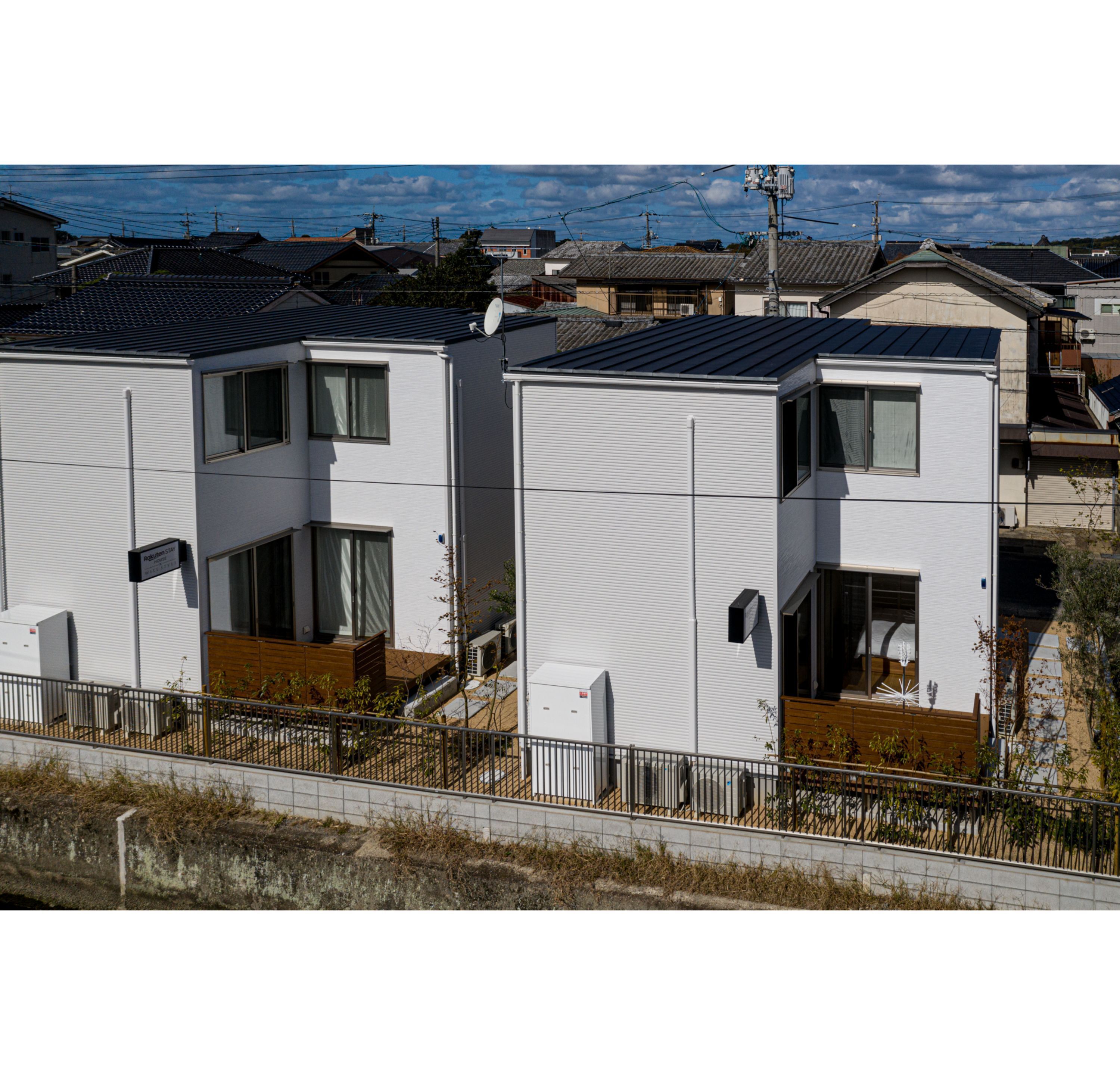 A modern residential building with a flat roof, large windows, and a visible satellite dish.