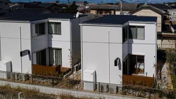A modern residential building with a flat roof, large windows, and a visible satellite dish.
