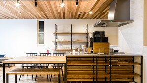 A modern kitchen with wooden flooring, a central island, and a dining area with benches. - Rakuten STAY HOUSE x WILLSTYLE Haginishitamachi (Hagi)