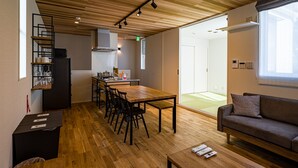 A modern interior with a wooden ceiling, a dining area with a table and chairs, a kitchenette, and a sofa. - Rakuten STAY HOUSE x WILLSTYLE Haginishitamachi (Hagi)
