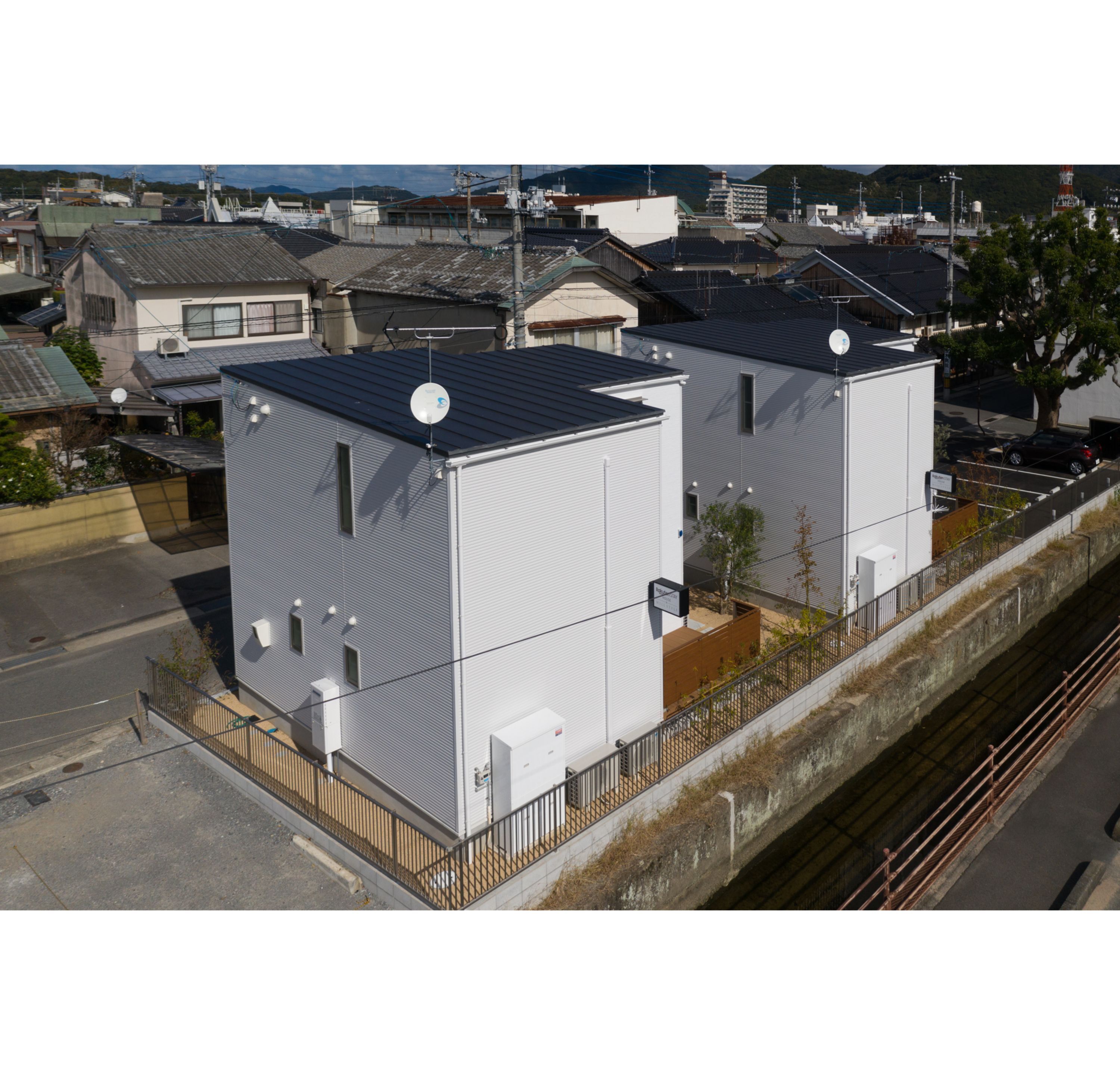 Two industrial-style buildings with flat roofs, located adjacent to a railway track.