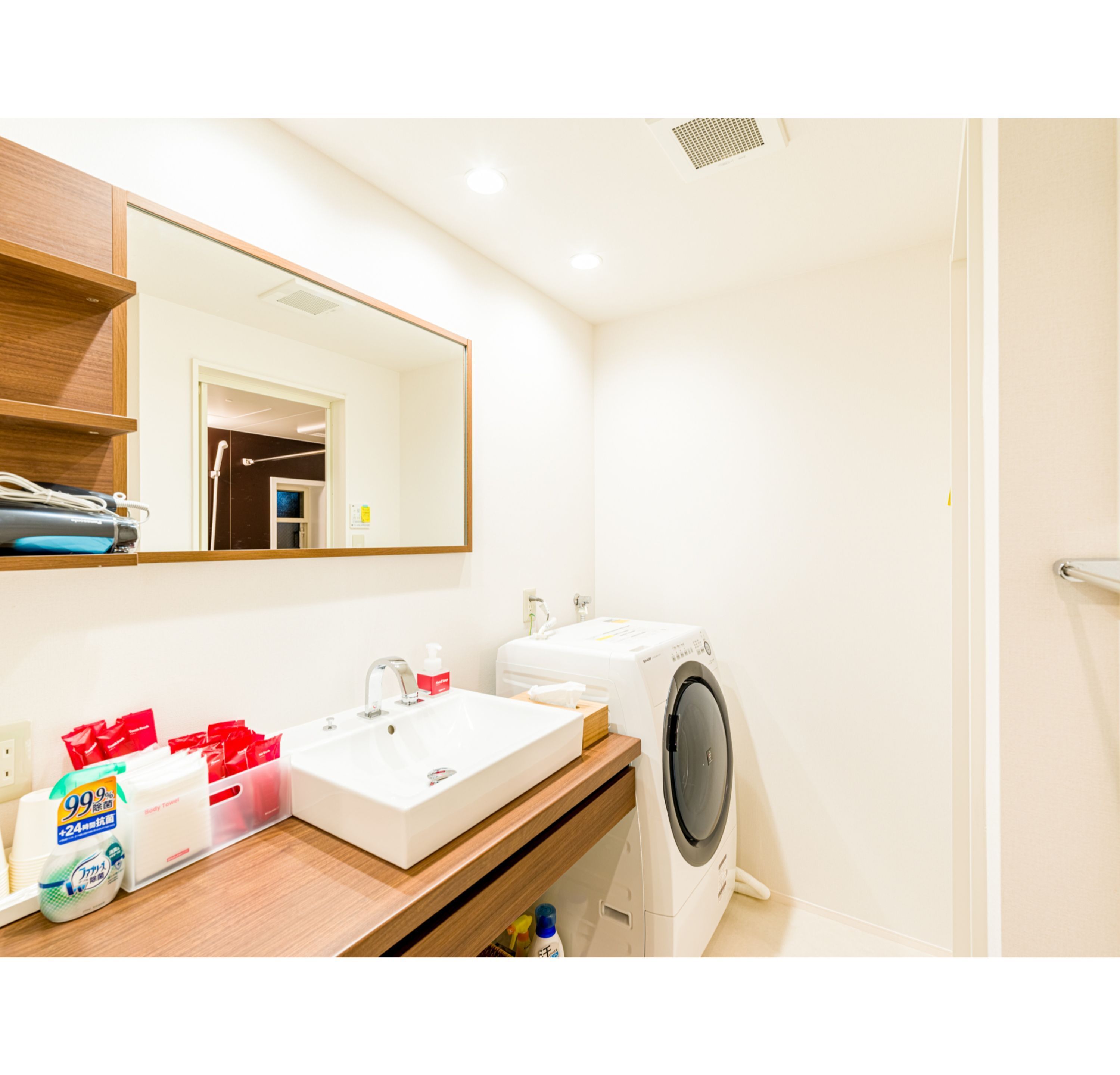 A modern bathroom with a sink, mirror, and washing machine.