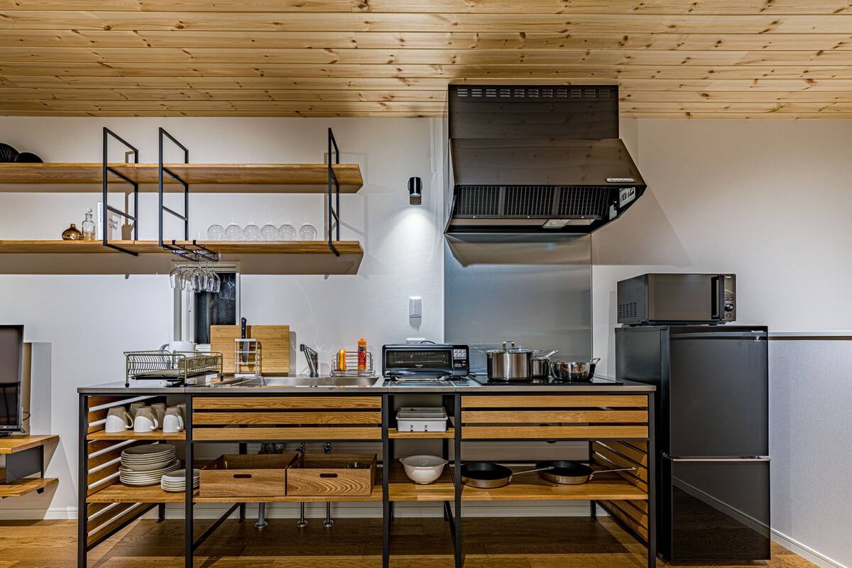Eine moderne Küche mit Holzböden, einem eingebauten Herd und einem Edelstahlkühlschrank.