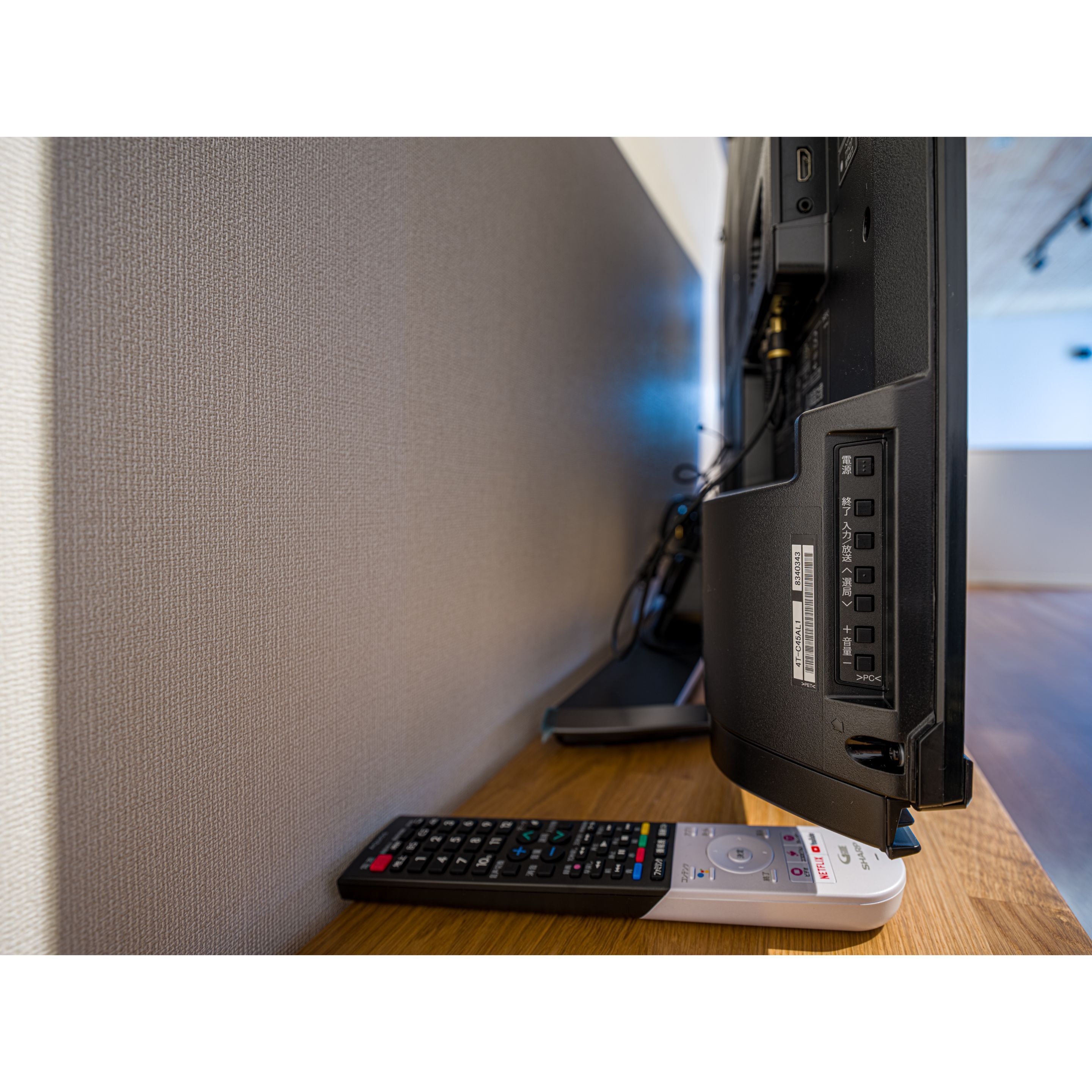 A remote control and a computer monitor on a wooden surface.