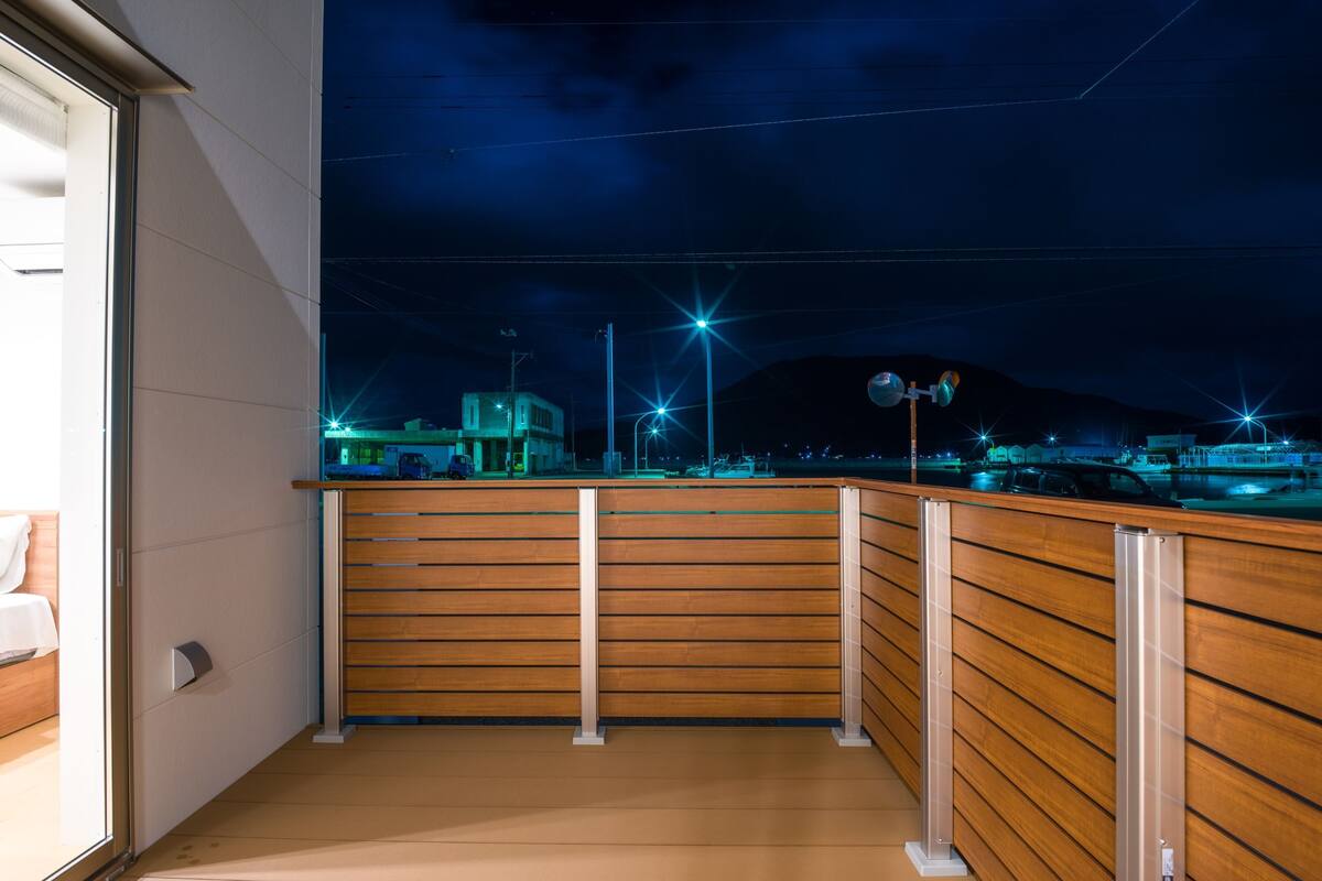 Ein Balkon mit Holzbalkonverkleidung, Blick auf eine nächtliche Skyline und einen klaren Himmel.