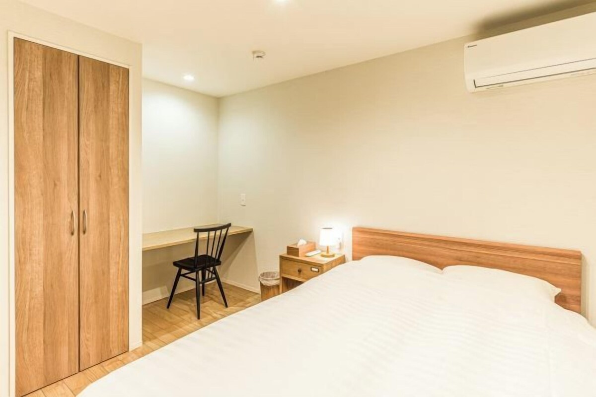 Un dormitorio con cama, escritorio, silla, mesita de noche y armario.