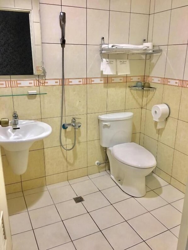 Um banheiro pequeno com pia, vaso sanitário e chuveiro.
