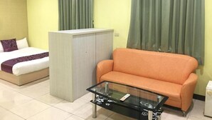 A room with a bed, an orange sofa, a glass coffee table, and a wardrobe. - Rural Area Hotel (Zhuqi)