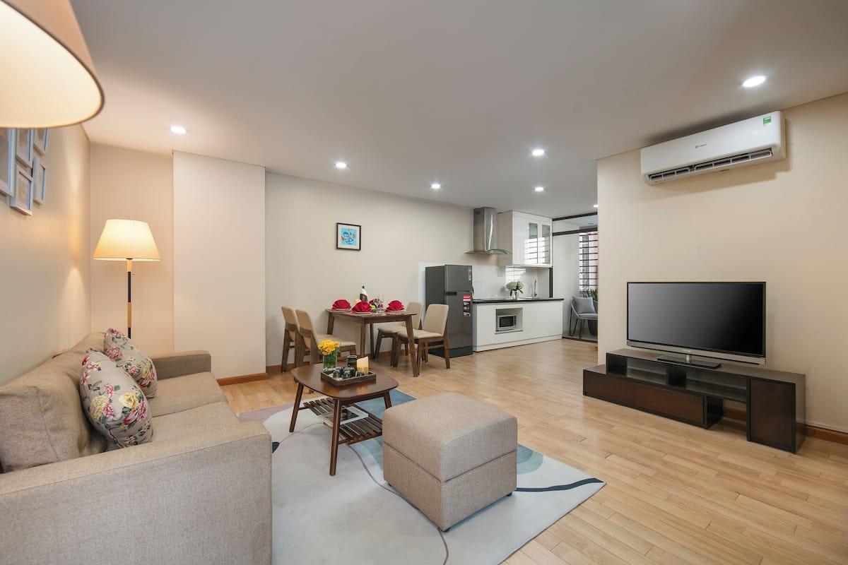 Uma sala de estar moderna com sofá, televisão e espaço de jantar.